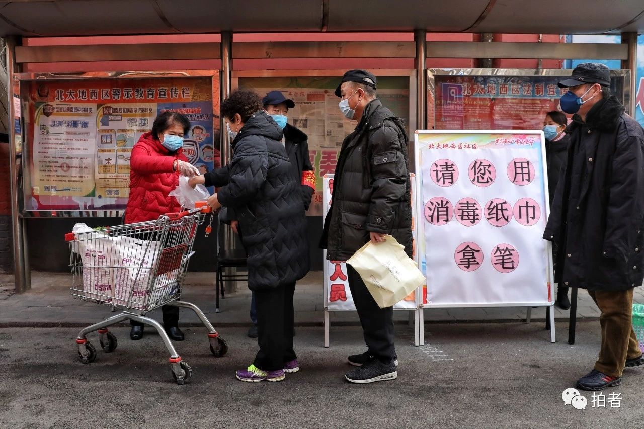 △2月12日,丰台区北大地三里 社区。南门,社工为进入 社区。的住民丈量体温。拍照/新京报记者王飞