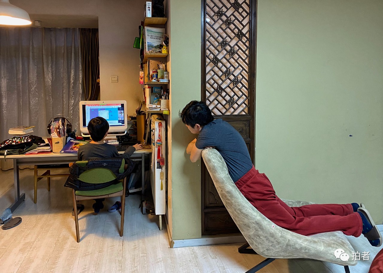 △2月13日,向阳区一小区住户内,一位父亲在看孩子上英语网课。拍照/新京报记者王荟