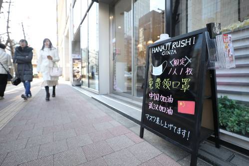  2月11日，在日本东京，银座的一个商铺门前的招牌上写着免费赠送口罩和为中国武汉加油鼓劲的内容。新华