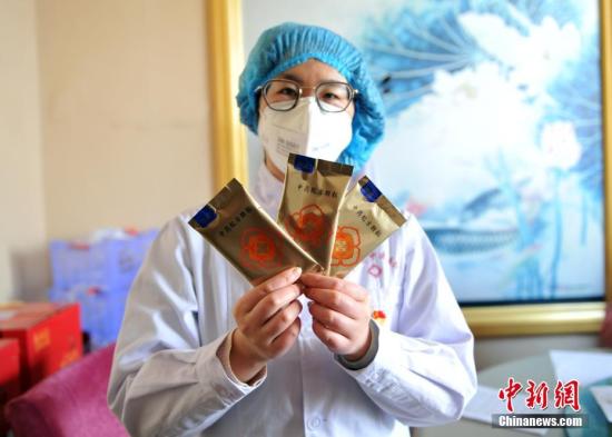 资料图:医护人员展示根据《新型冠状病毒感染的肺炎诊疗方案》研制的中药制剂。中新社记者 韩冰 摄