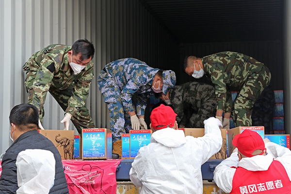 军人和志愿者们共同搬运物资。