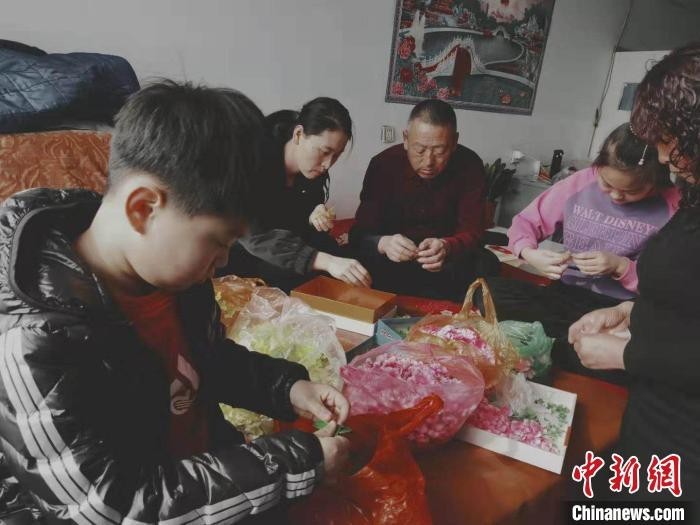 一家老小围坐在一起做手工绢花。 受访者供图
