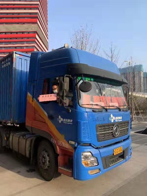 挂着沪牌的货车为上海医疗队送来军大衣等物资，临别之际，货车司机举着“武汉加油”的标语向上海医疗队队员表达问候和敬意。