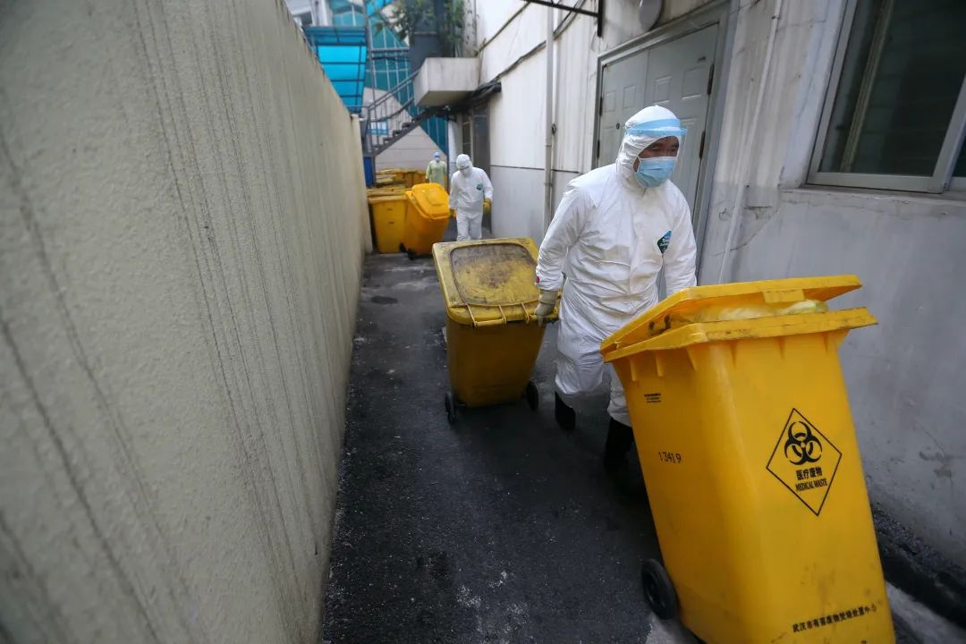武汉市红十字会医院,后勤人员在清晨把提前装桶的医疗废物拖出准备装车转运。由于量太大,多个省市有医疗废物处置资质的队伍驰援武汉,义务协助医院转运。(摄影:崔萌)