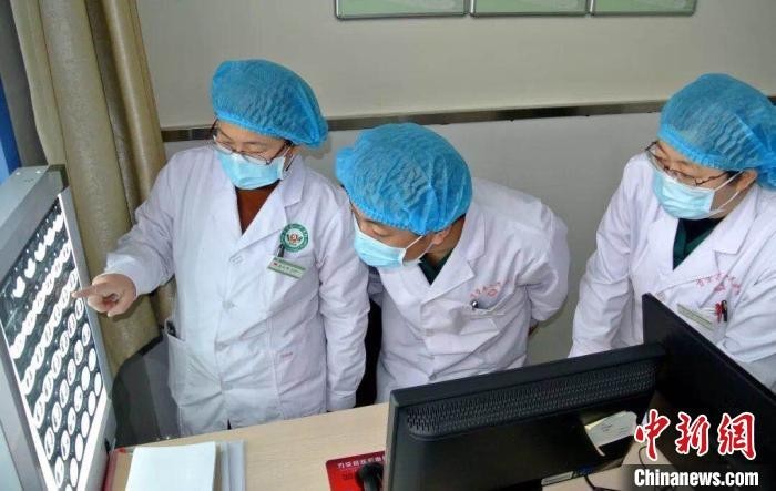秦江华(左一)和科室医生讨论患者病情。 万荣县人民医院供图