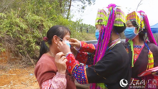 邓继妍给村民送口罩,并指导如何佩戴。上思县融媒体中心供图