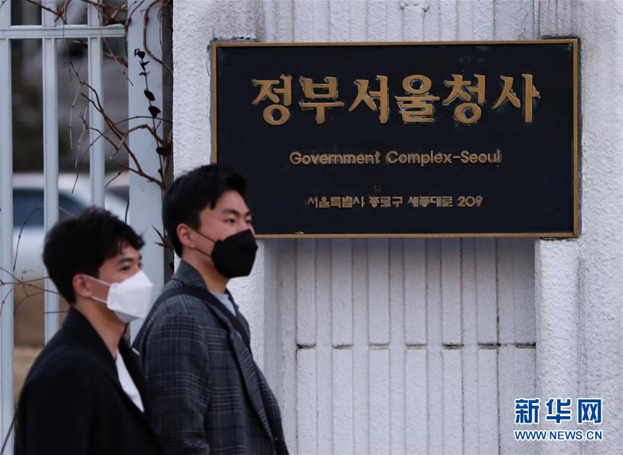 2月23日,行人从韩国首尔中央政府外墙走过。