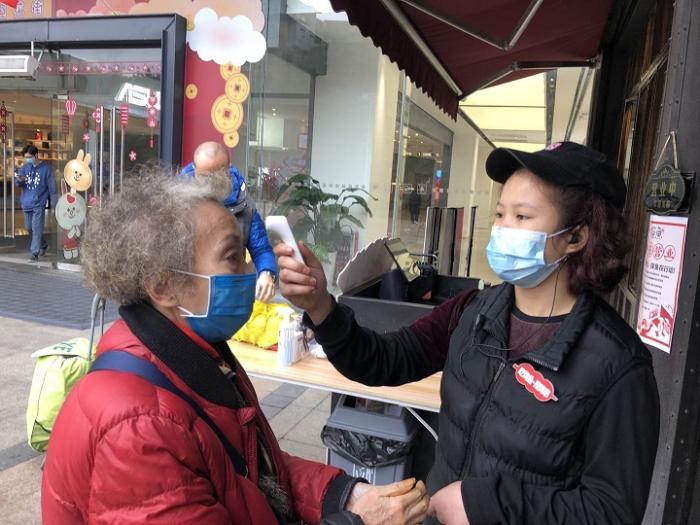 （店员为顾客测量体温）