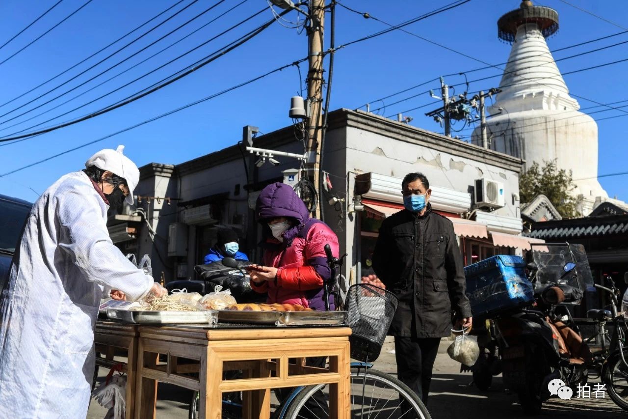 △2月17日，西城区宫门口西岔胡同，居民戴口罩购买食品。摄影/新京报记者浦峰