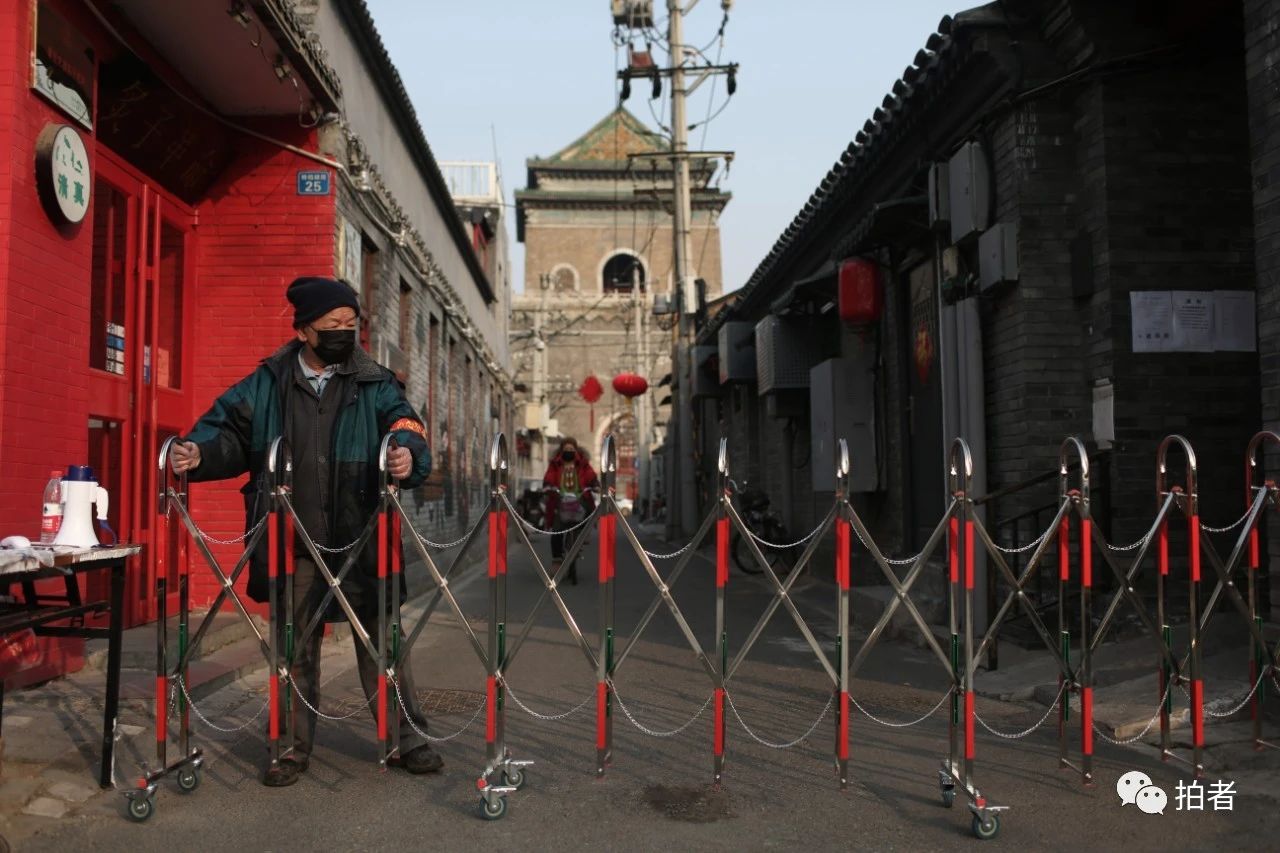  △2月25日，旧鼓楼大街，一位工作人员在铃铛胡同值守。因疫情防控需要，胡同口设置了24小时值班岗，进出居民须出示出入证，测量体温后方可通行。摄影/新京报记者薛珺
