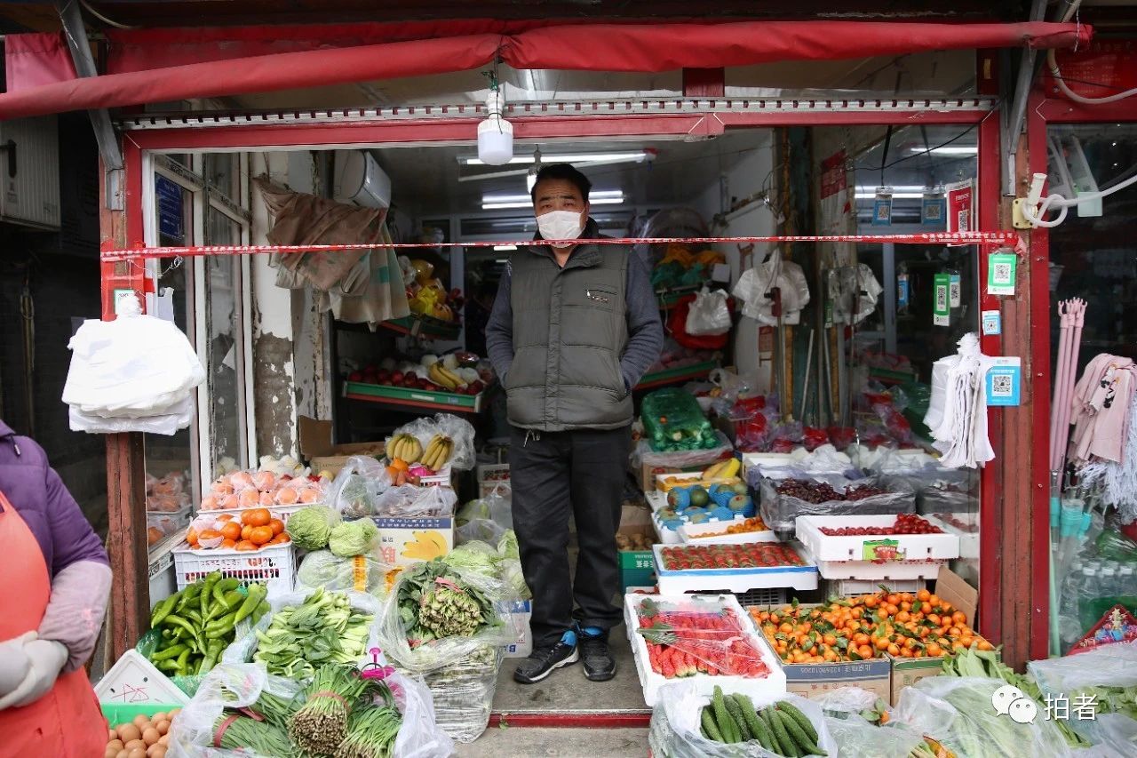  △2月27日，大栅栏街道三井社区，一家菜店拉起隔离线，社区居民在线外安全距离买菜。摄影/新京报记者郑新洽
