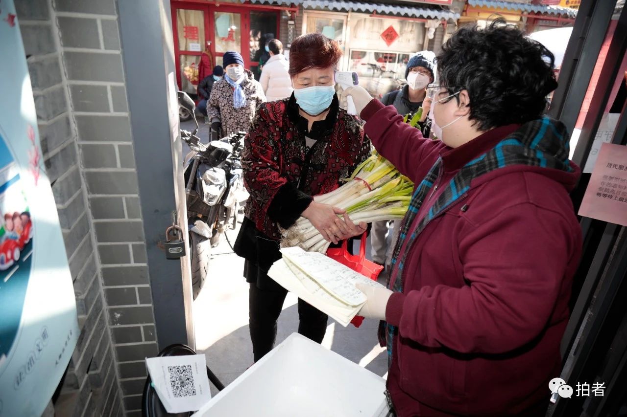 △2月22日，大栅栏街道养老助残服务中心银鹤苑门口，工作人员将居民预订的蔬菜放入箱子，居民测温无异样后，“无接触”取走。摄影/新京报记者王嘉宁