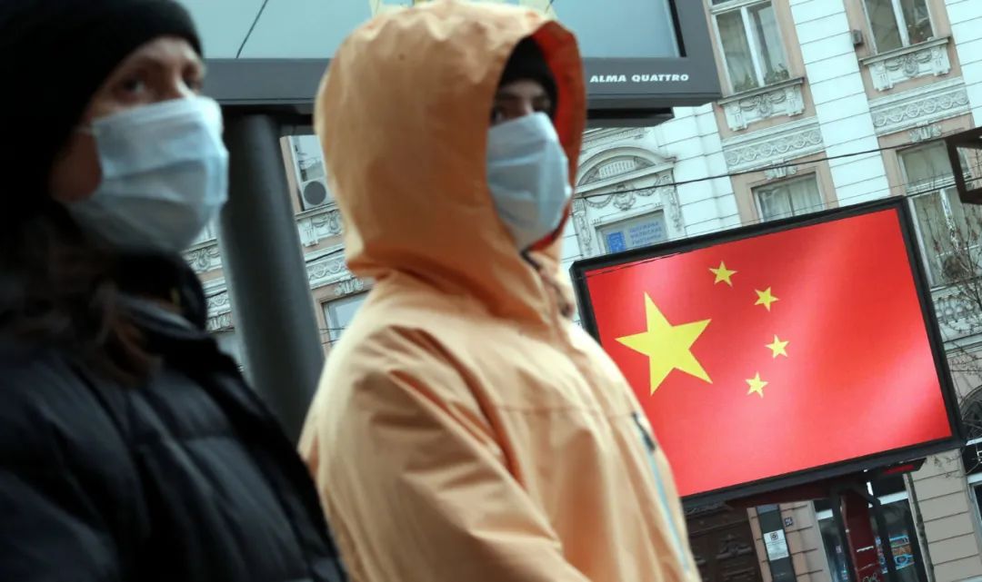 3月23日,在塞尔维亚贝尔格莱德,人们路过一处显示中国国旗的显示屏。新华社发(内马尼亚摄)