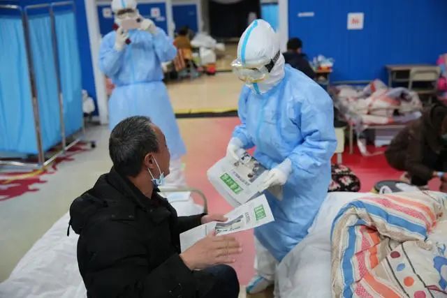  在方舱医院直播时，前线记者张赫给患者送上了当天出版的健康时报。人民日报记者张武军摄