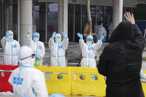 2月26日,武汉首个中医方舱医院首批治愈患者出院,图为治愈患者(前右)向江夏方舱医院的医护人员挥手作别。新华社记者 沈伯韩 摄