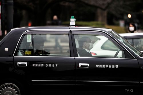 2月25日,在日本东京的一辆出租车内,乘客(左)和司机都戴着口罩。新华社记者 杜潇逸 摄