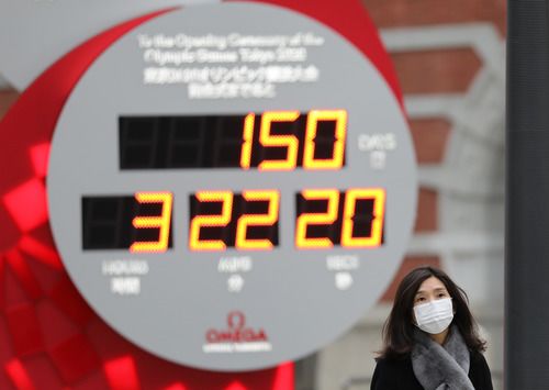 2月25日,在日本东京,行人戴口罩经过显示东京奥运会倒计时的电子屏。新华社记者杜潇逸摄
