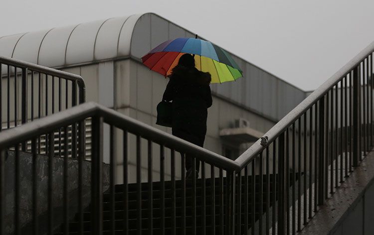 西二旗大街人行天桥上,市民打开彩色雨伞。