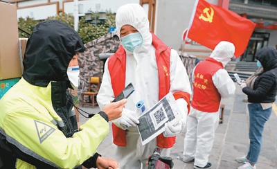 图为4月11日，工作人员在武汉中华路街居民小区封控卡点，让出小区的人员扫描健康码。新华社记者 王毓国摄
