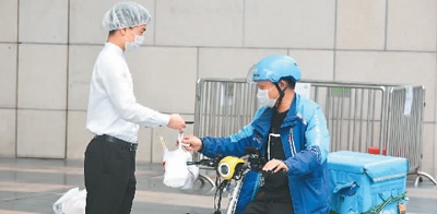 日前,深圳福田某购物中心内一家餐厅员工将打包好的餐点交给外卖小哥。 新华社记者 赵瑞希摄