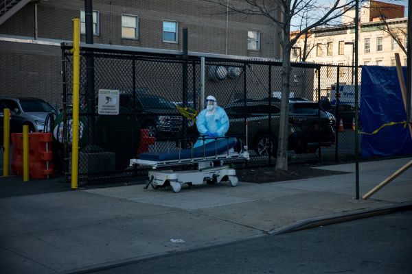 4月6日，在美国纽约一家医院外，医护人员运送死者遗体后推着空床返回。新华社发