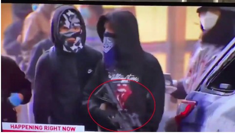 ▲蒙面抗议者偷走警用步枪后,在街边观望。(视频截图)