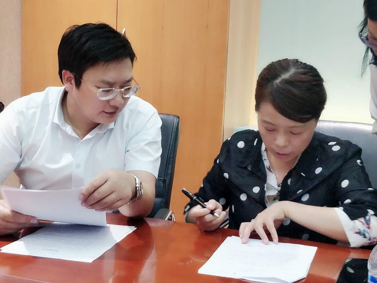 ▲周兆成律师(左)与许女士签订授权委托书。受访人供图