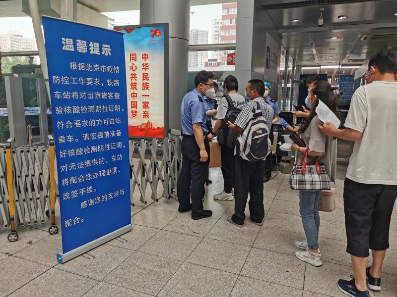 北京南站二楼进站口铁路工作人员在检查核酸检测阴性证明。