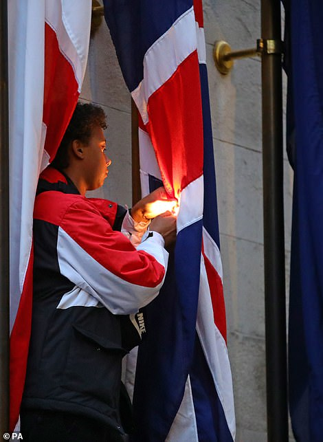 一名抗议者被拍摄到爬上国家战争纪念碑,并点燃了英国国旗。(图源:每日邮报)