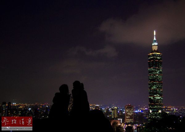 资料图片:图为两名游客在台北象山上观看台北市区夜景。(图片来源:新华社发)