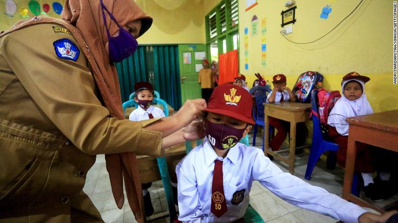 一位印度老师在为学生固定口罩（美国有线电视新闻网）