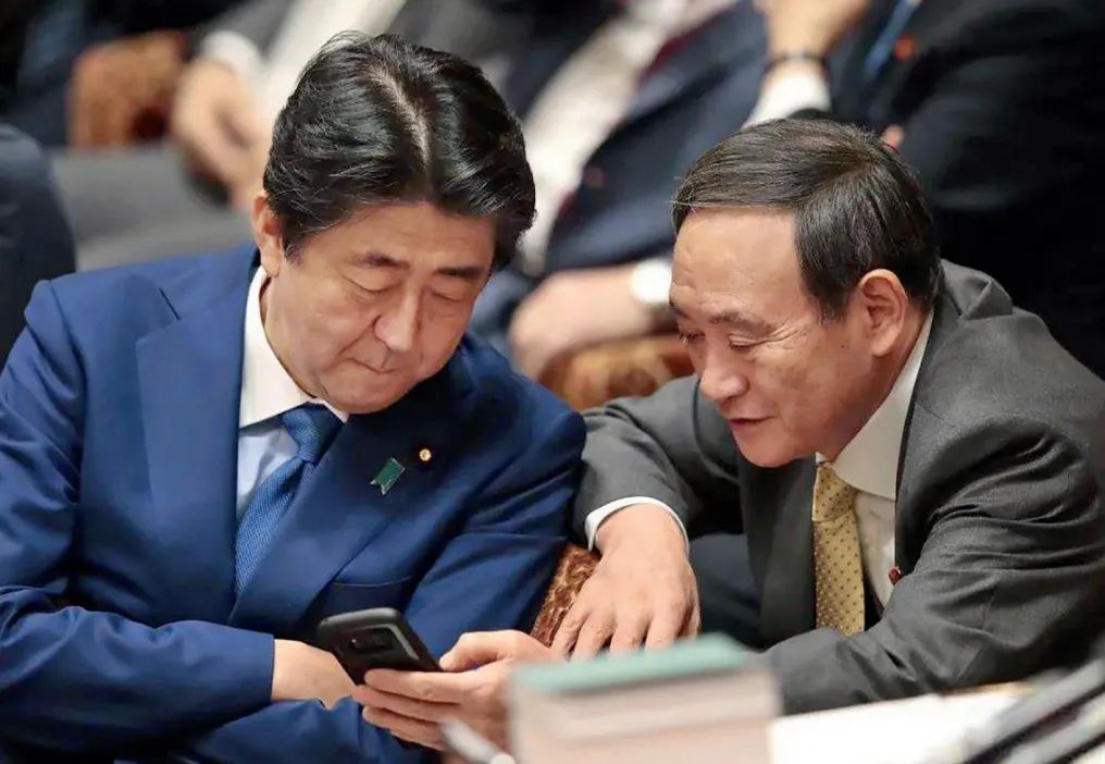 ·安倍晋三(左)与菅义伟在会议上讨论。