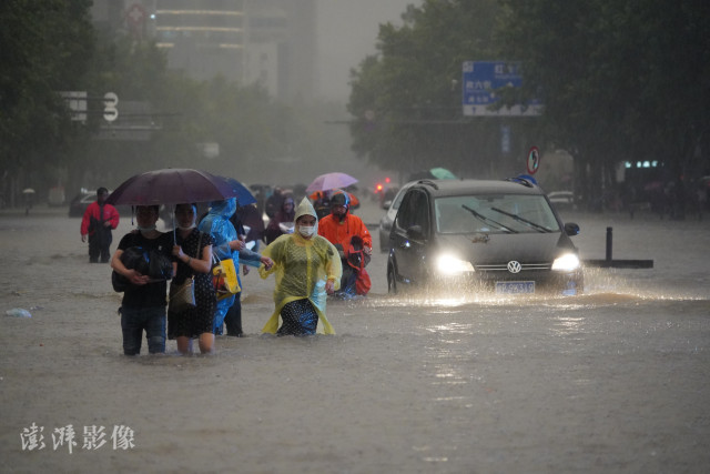 7月20日,河南强降雨持续,省会郑州16时至17时一个小时降水量达201.9mm,单小时降雨量超过日历史极值。图为市民在积水中趟行。图自澎湃影像。