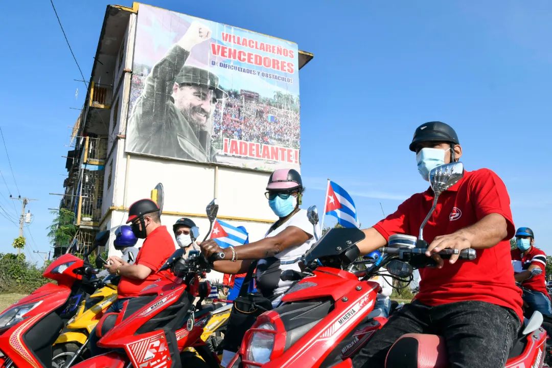  4月25日，人们骑摩托车在古巴中部城市圣克拉拉参加游行。古巴多地4月25日举行游行活动，几千名参与民众要求美国解除对古巴近60年封锁。新华社发（华金·埃尔南德斯摄）