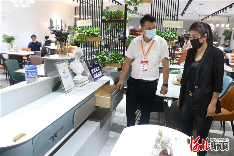 工作人员正在向客户介绍企业自主研发设计的客厅家具.通讯员邢亚南摄