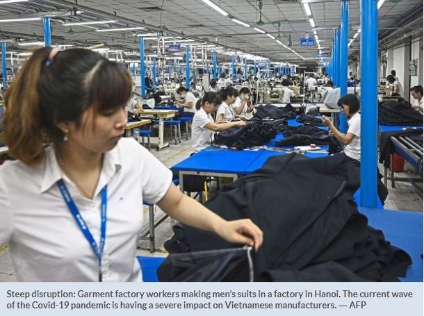 河内一家工厂的服装厂工人正在制作男士西装(报道截图)