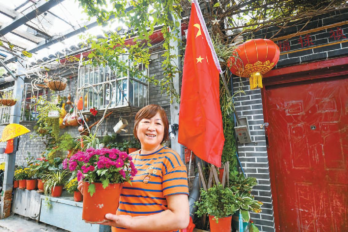 国庆到来之际，东城区流水巷居民安素云在自家门前摆好鲜花，挂出国旗，共庆祖国生日。邓伟 摄