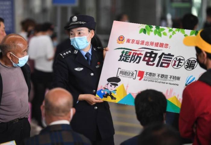 (4月29日,在南京站候车室,民警向旅客普及防范电信诈骗知识。来源:新华社)