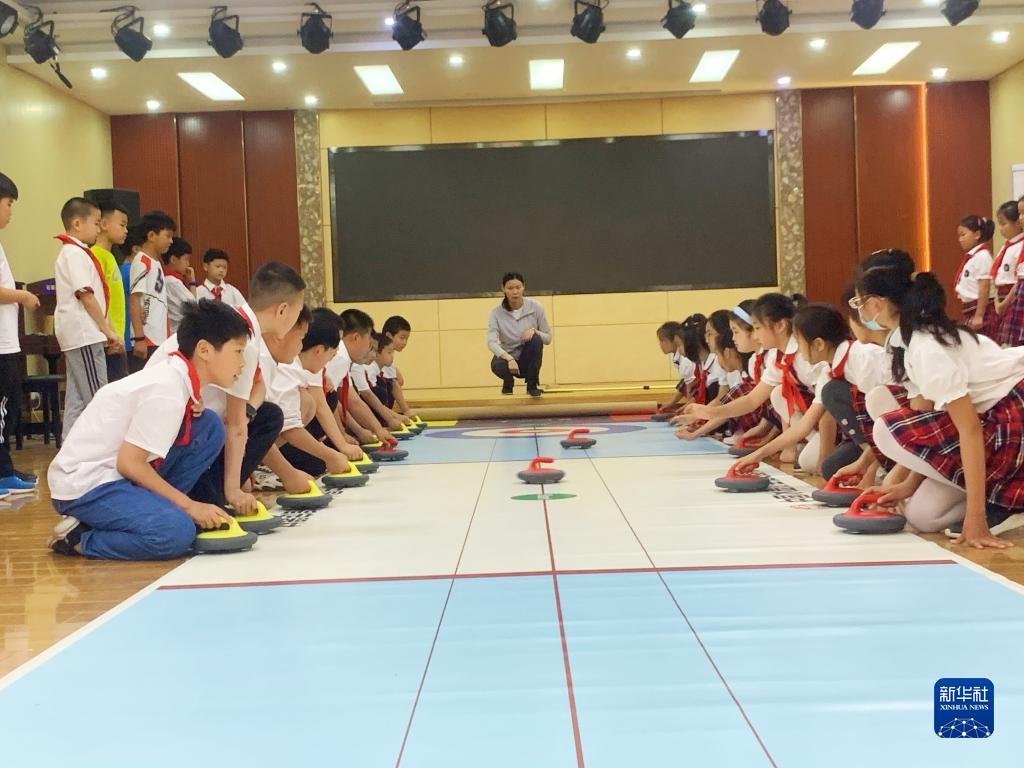 石家庄市神兴小学参加冰壶运动课后服务的孩子们正在听专业老师讲解。(程世瑶 摄)