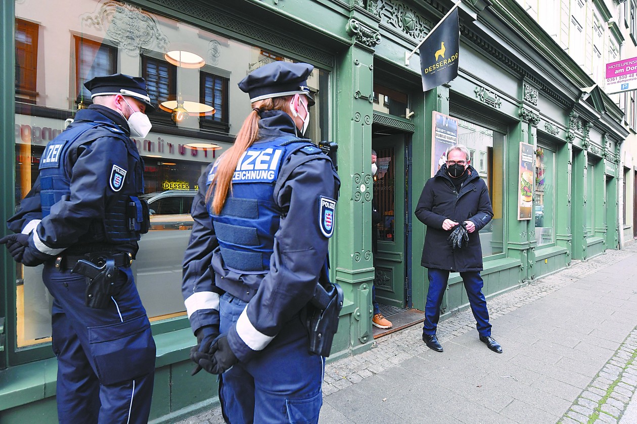 德国新冠肺炎疫情急剧恶化,25日报告单日新增确诊病例首次突破7万例,累计死亡病例超 过10万例。图为图林根州首府爱尔福特的警务人员在进行防疫检查。