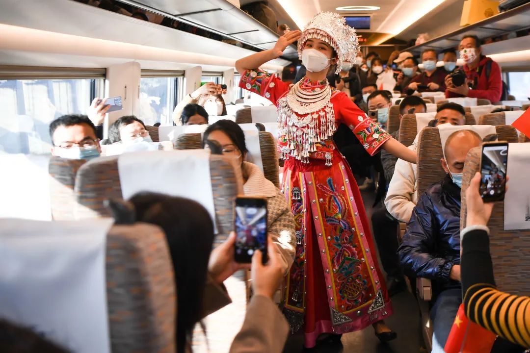 ▲12月6日，工作人员身着苗族服饰在首趟正式运营的张吉怀高铁列车上为乘客表演。新华社记者 薛宇舸 摄