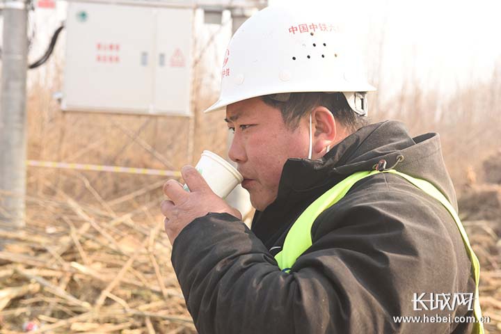 喝杯后勤保障团送来的热水，稍作休整再使劲儿干。张俊豹 摄