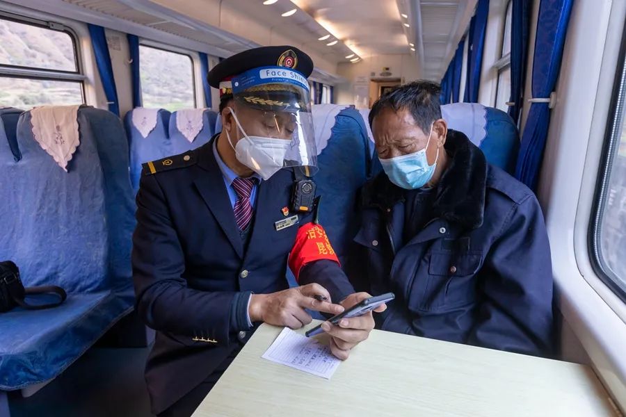 列车长杨兆祥在帮乘客购买返程车票。李浩 摄