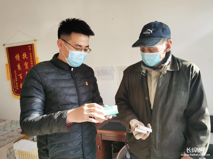 东堤村驻点干部闫世雄（左）为村里老人送药，并叮嘱服用次数和剂量。
