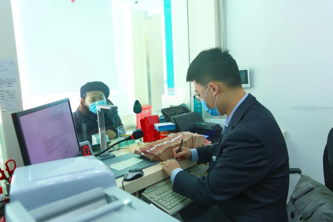图为农业银行大连庄河支行的工作人员为顾客办理业务。