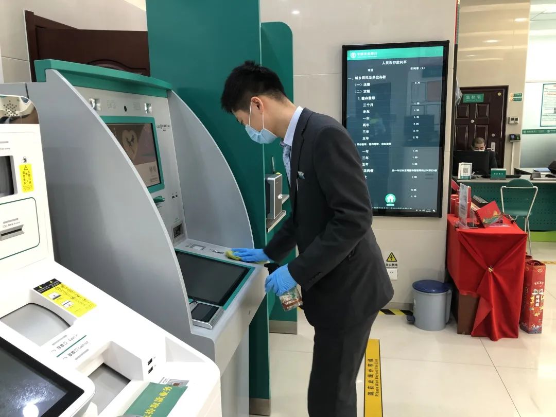 图为农业银行大连甘井子汇达街支行员工为自助机消毒。