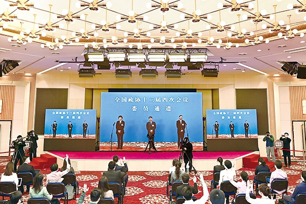 3月7日上午,全国政协十三届四次会议第二场“委员通道”采访活动在北京人民大会堂新闻发布厅举行。图为记者在分会场屏幕前举手提问。 新华社记者 贺长山 摄