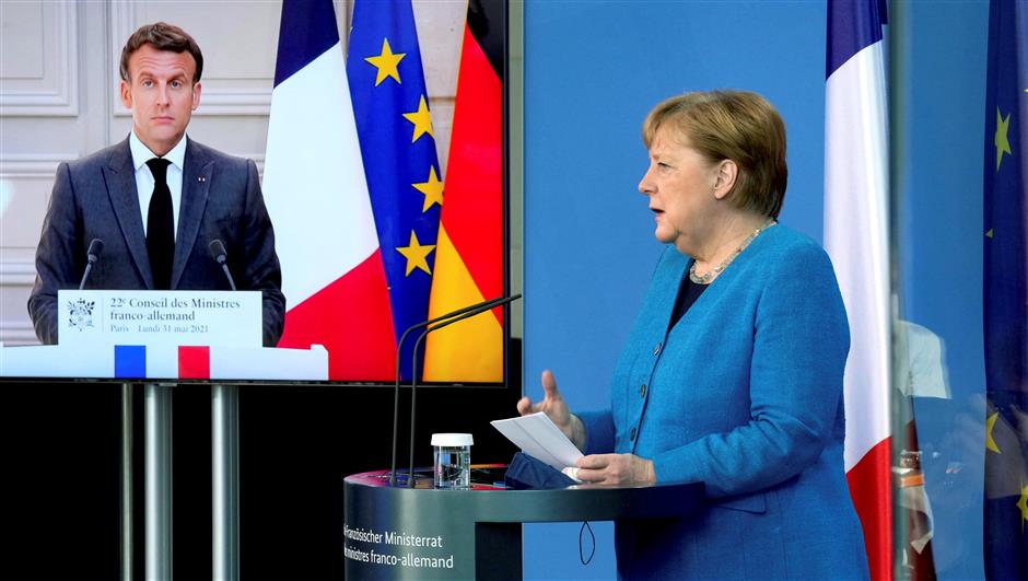 French President Emmanuel Macron (left) is seen on a video screen during a joint press conference with German Chancellor Angela Merkel as part of a virtual Plenary Session of the Franco-German Council of Ministers in Berlin on May 31. AFP