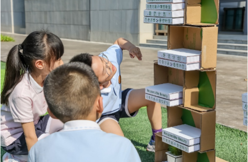 (学生围观用“小绿宝”搭成的创意书架)
