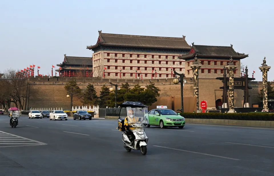 2022年1月10日,快递人员骑行在西安市南门外道路上。随着疫情逐渐好转,西安市推进商贸服务业、邮政快递业、餐饮业等有序复工复产。(新华社记者 陶明/图)